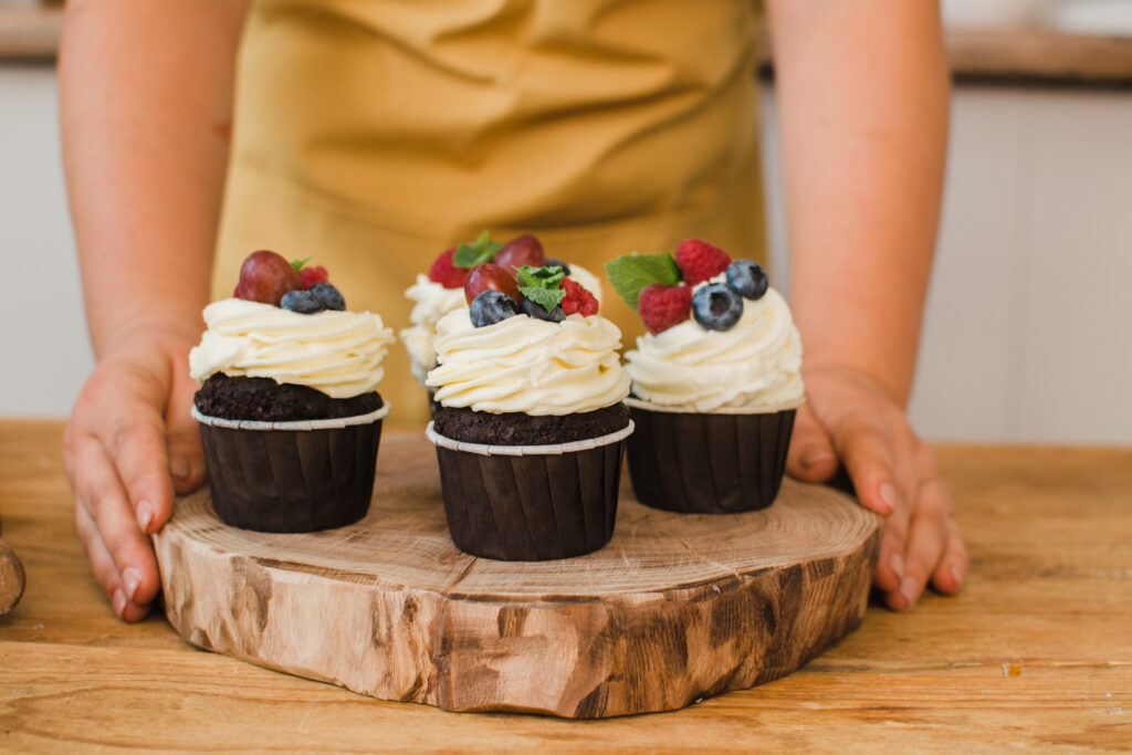 Recyclable Muffin Cups That Keep Large Scale Baking Reliable close up on hands of female pastry chef in white gown with muffin or a cupcake decorated with wild berries