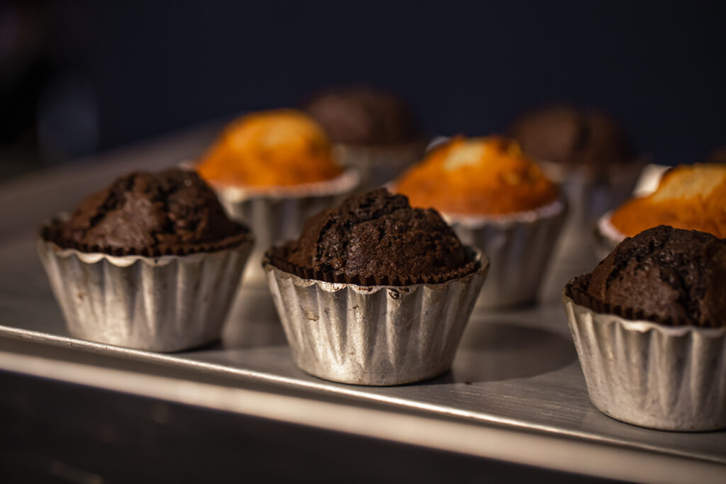 Food Grade Paper Muffin Cups Built for High Volume Professional Baking freshly baked muffins in metal molds close ups in a bakery.