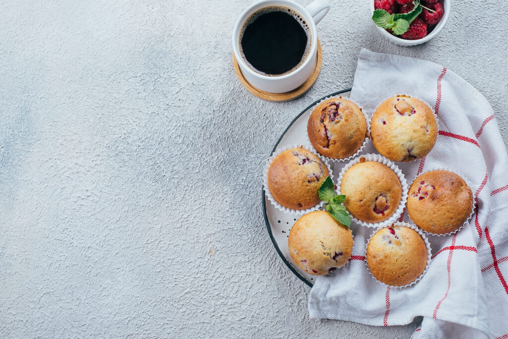 delicious breakfast food concept. coffee, raspberry muffins on light concrete background. top view