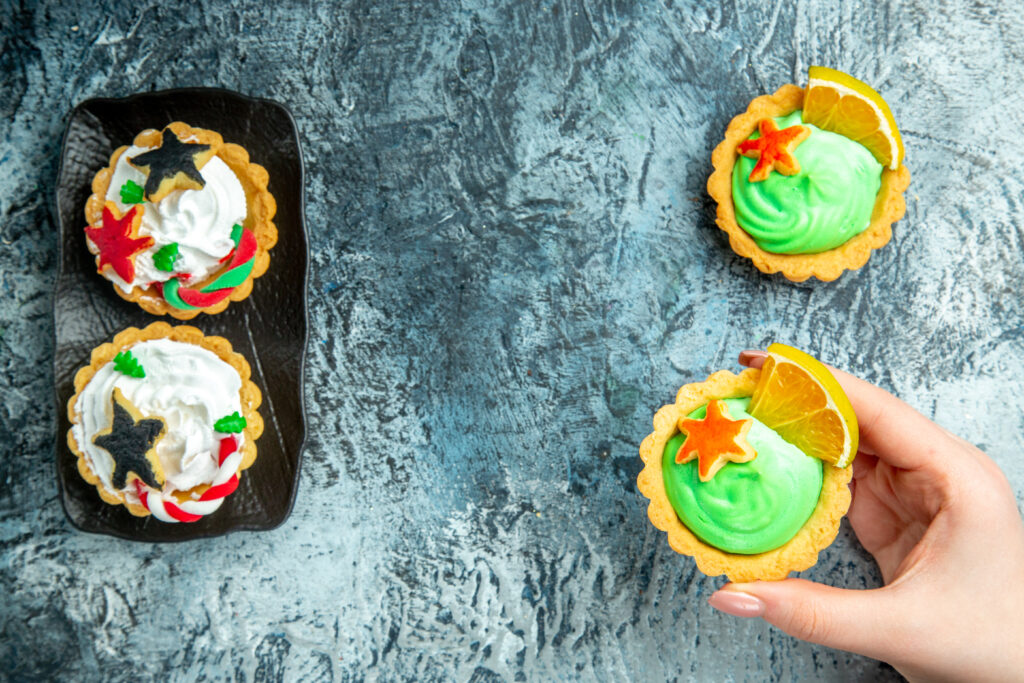 Recyclable Muffin Cups That Deliver Consistency Batch After Batch top view xmas tarts black plate small tart female hand grey table free space
