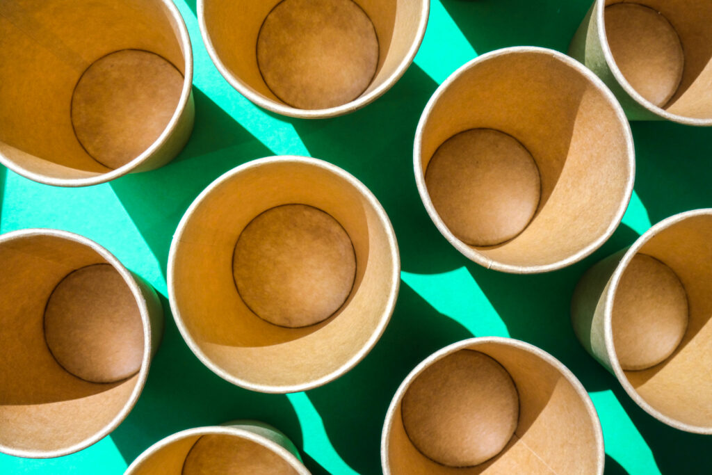 empty recyclable paper cups on green background. many takeaway cups for drink. eco friendly. zero waste plastic free concept.